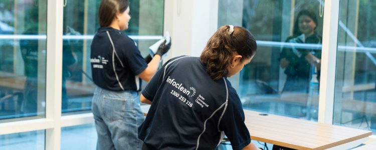 Infoclean commercial cleaning team sanitising office desks and windows, delivering professional workplace cleaning services for businesses.